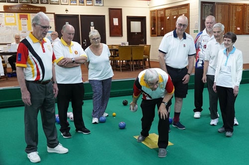 One of the coaches at Kingsthorpe Bowling Club showing how to deliver a bowl during an indoor bowling coaching session. All coaching is provided to beginners free of charge